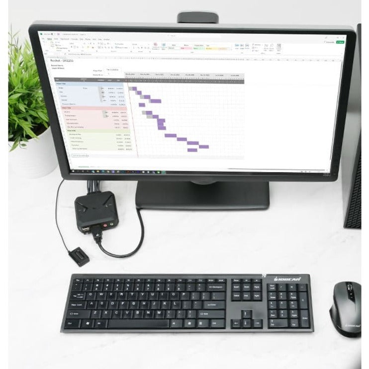 IOGEAR KVM switch in use with monitor, keyboard, and mouse showing productivity software