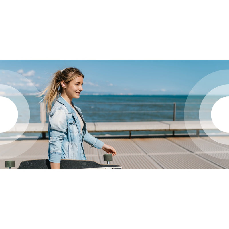 Person wearing Belkin earbuds outdoors near the ocean