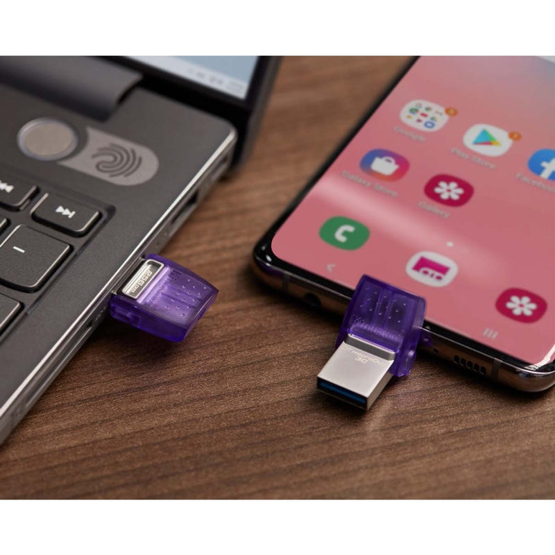 Kingston DataTraveler microDuo 3C connected to both laptop USB-A port and smartphone USB-C port on wooden surface