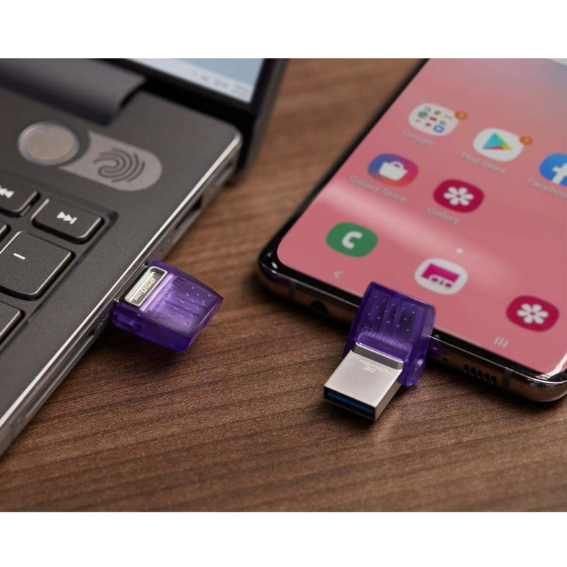 Kingston DataTraveler microDuo 3C shown connected to both laptop USB-A port and smartphone USB-C port on wooden surface