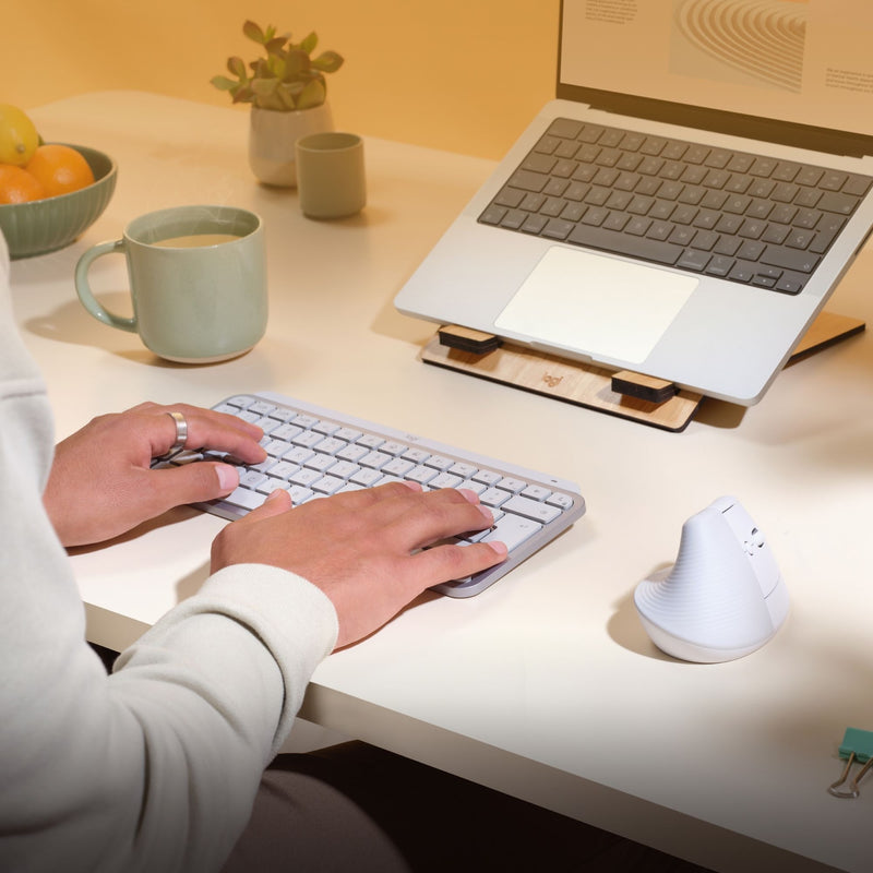 Complete workspace setup showing Logitech Lift mouse with Mac accessories and desk items