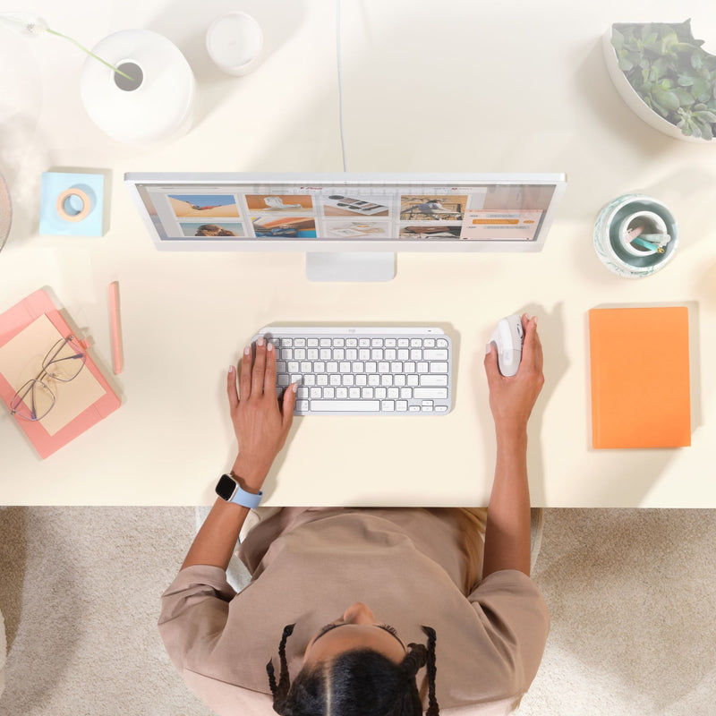 Top-down view of workspace with Logitech Lift mouse and Mac accessories