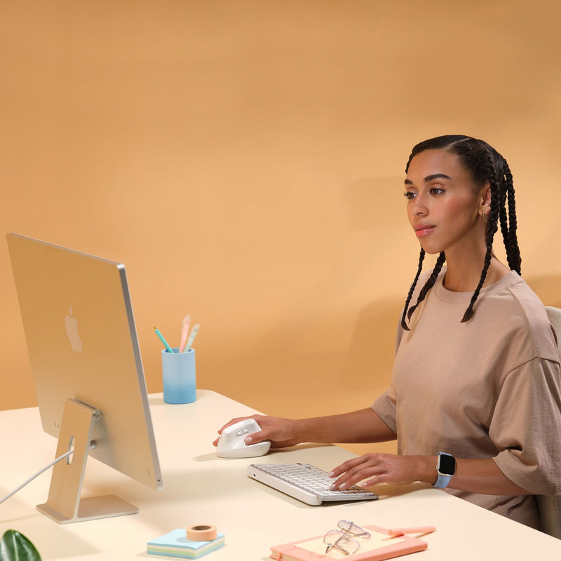 Person using Logitech Lift vertical mouse with Mac setup in a modern workspace