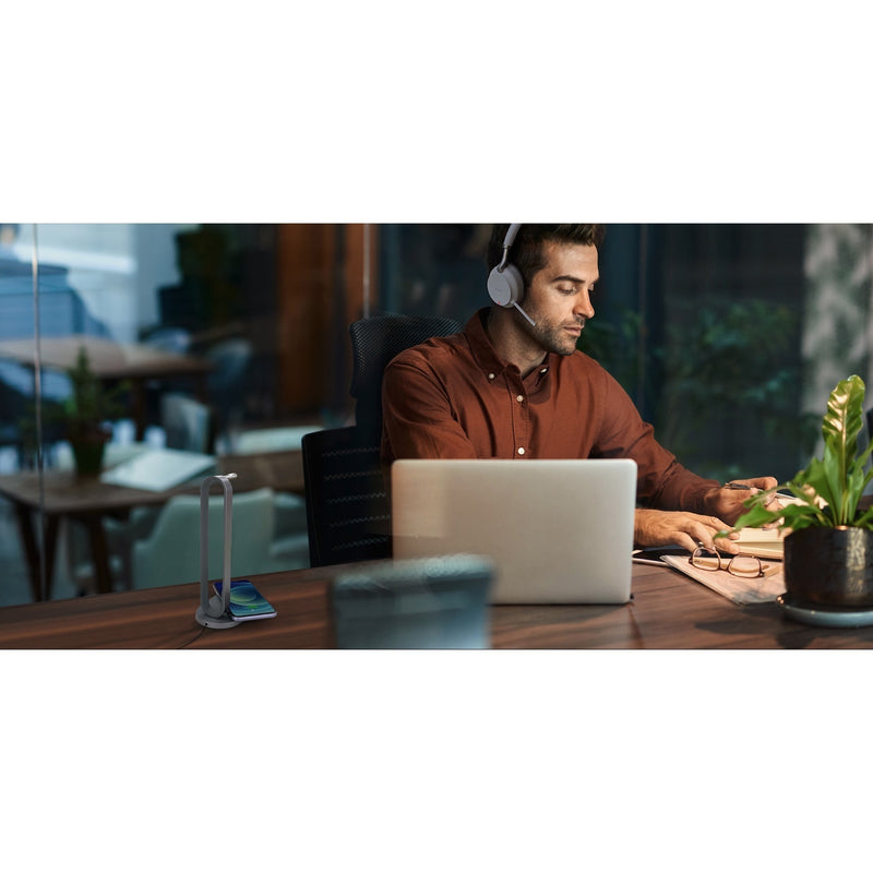 Professional using Yealink BH72 headset in modern office setting with charging stand