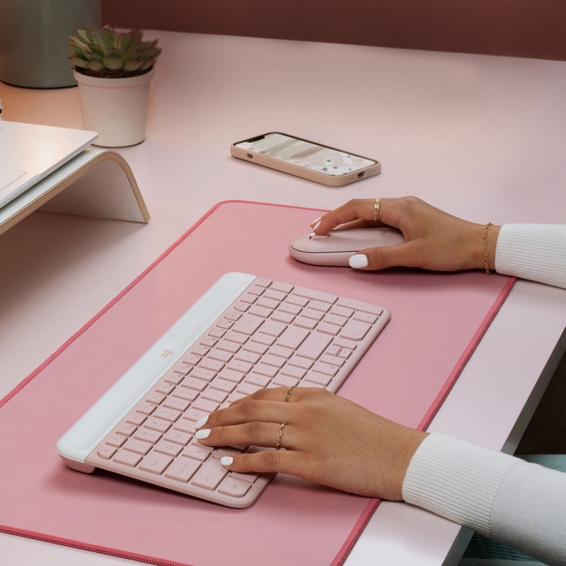 Close-up of hands typing on Logitech MK470 keyboard with mouse on pink desk mat