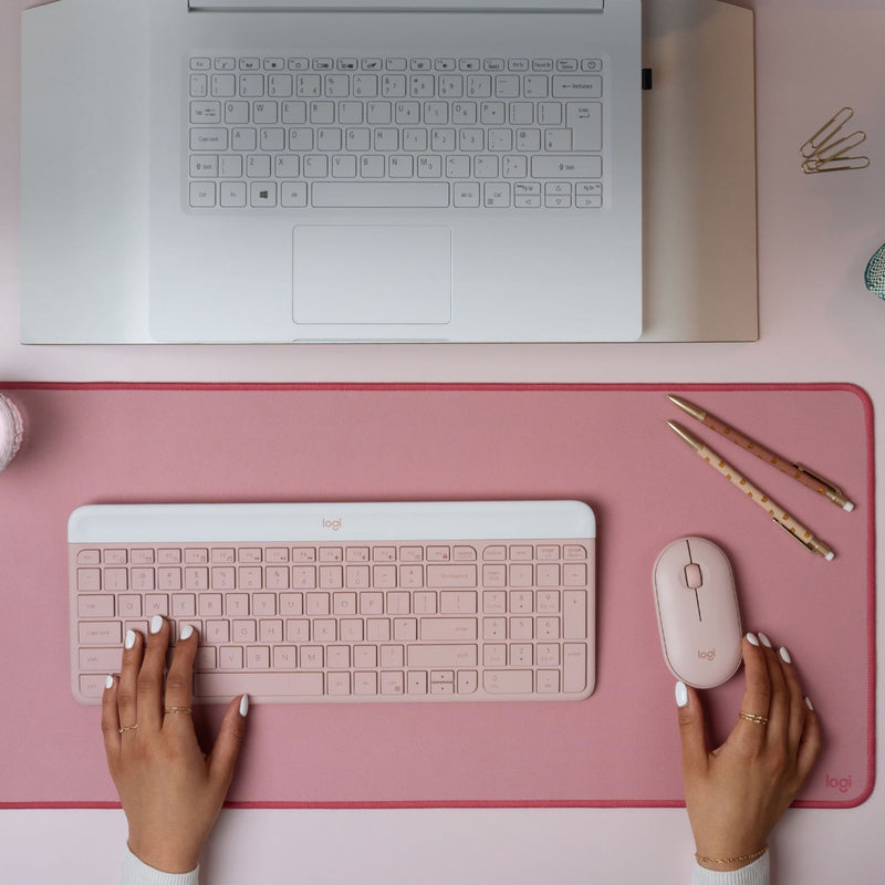 Overhead view of Logitech MK470 keyboard and mouse on pink desk mat with laptop and accessories