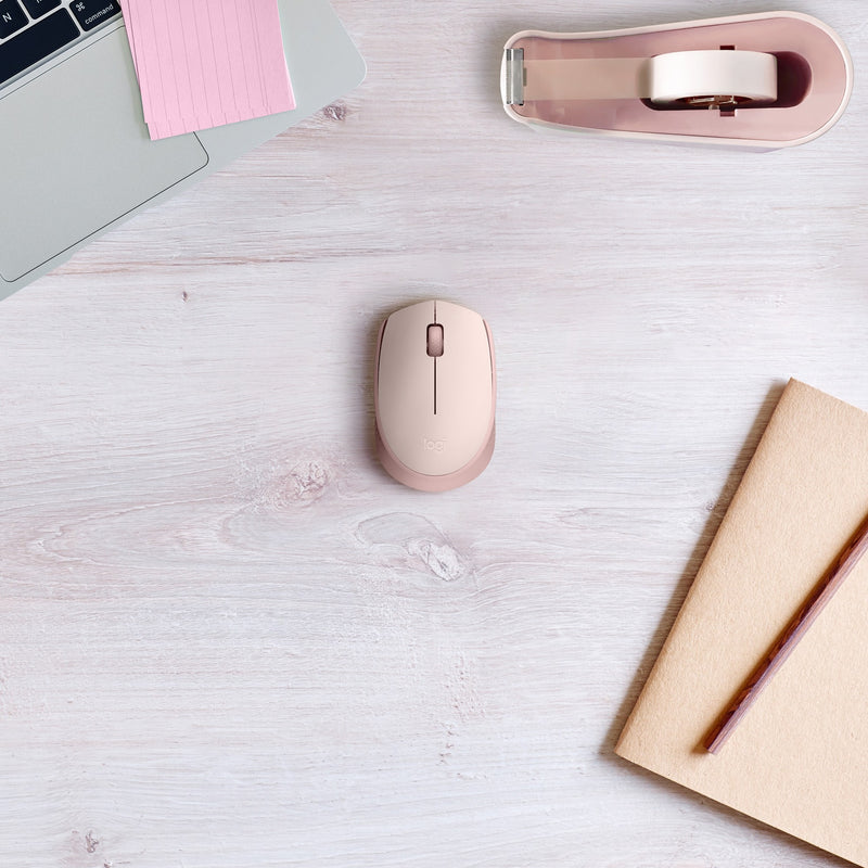 Lifestyle shot of rose gold M170 mouse on white desk with notebook and laptop