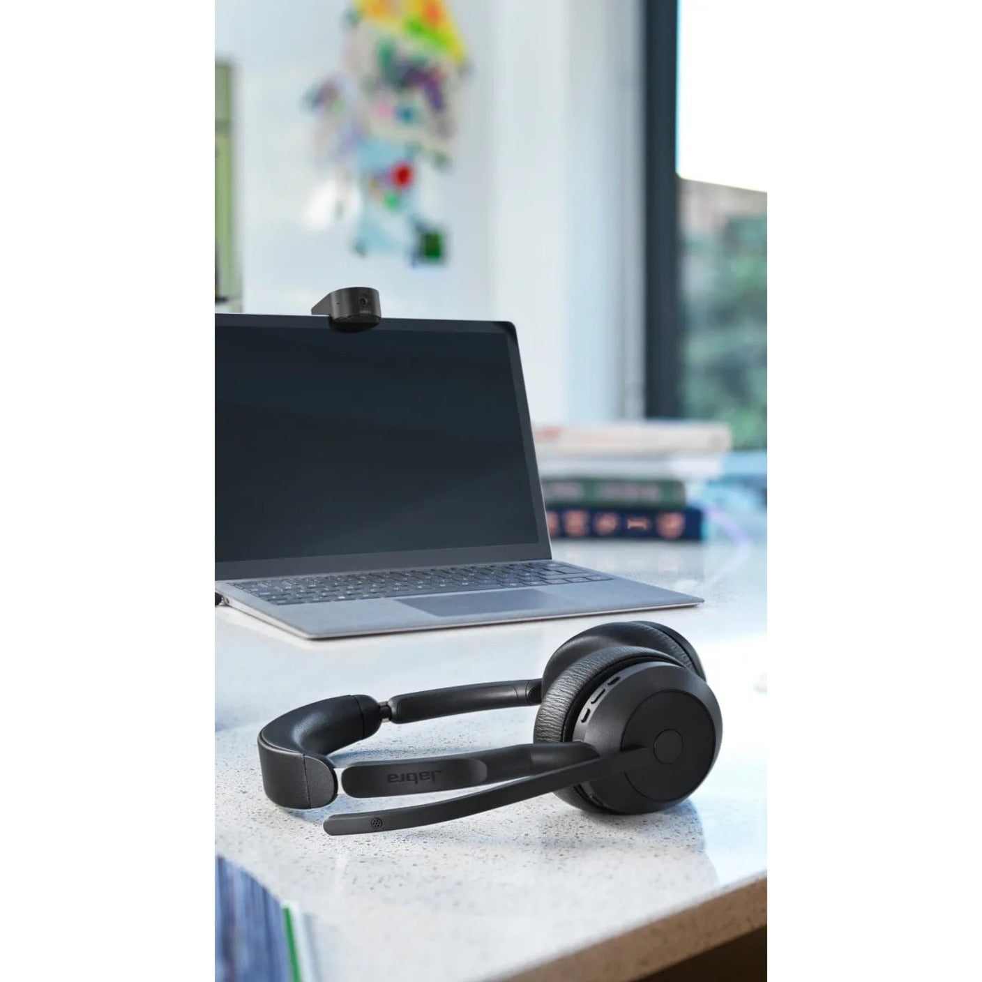 Jabra Evolve2 55 on desk with laptop and charging stand-alternate-image6