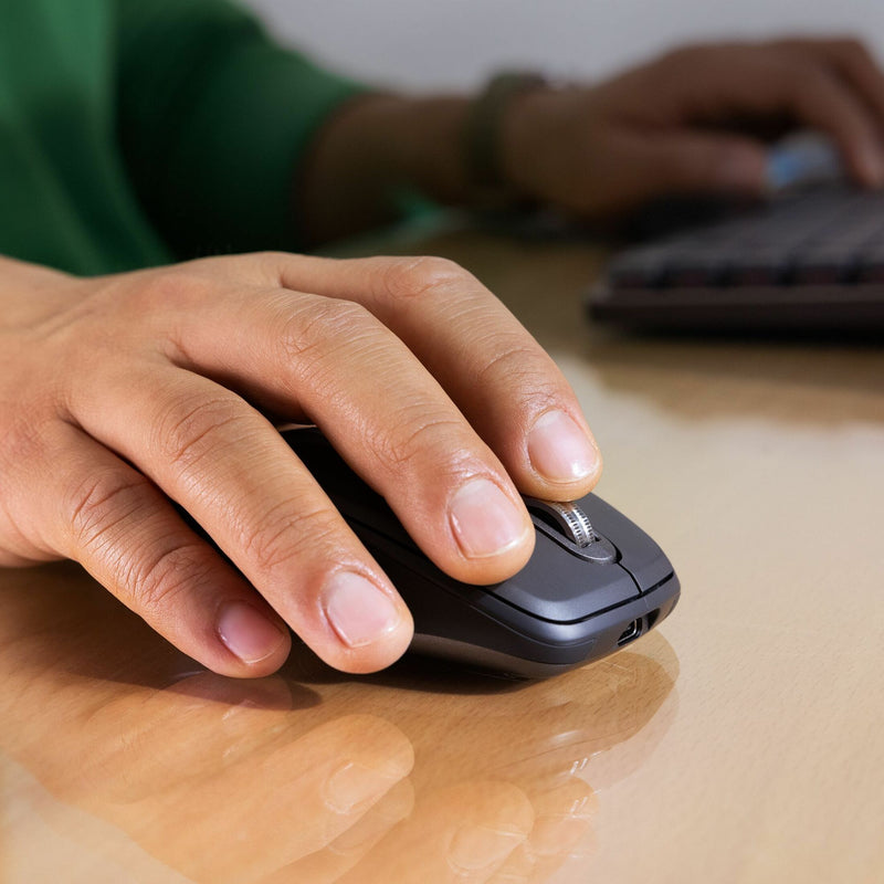 Close-up of hand using Logitech MX Anywhere 3S mouse on wooden desk