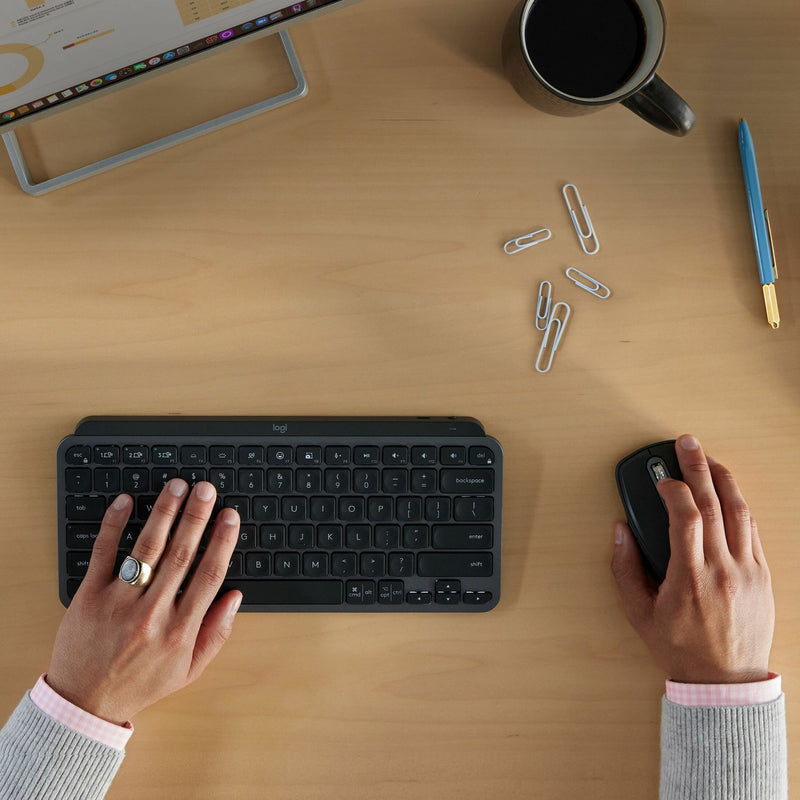 Hands using Logitech keyboard and MX Anywhere 3S mouse in workspace setting