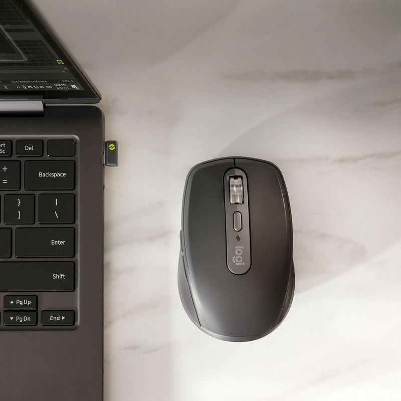 Logitech MX Anywhere 3S wireless mouse positioned next to laptop keyboard with Logi Bolt receiver