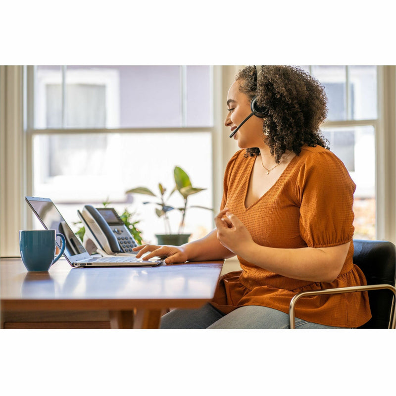 Person using Poly Edge E320 IP phone in a home office setting with laptop