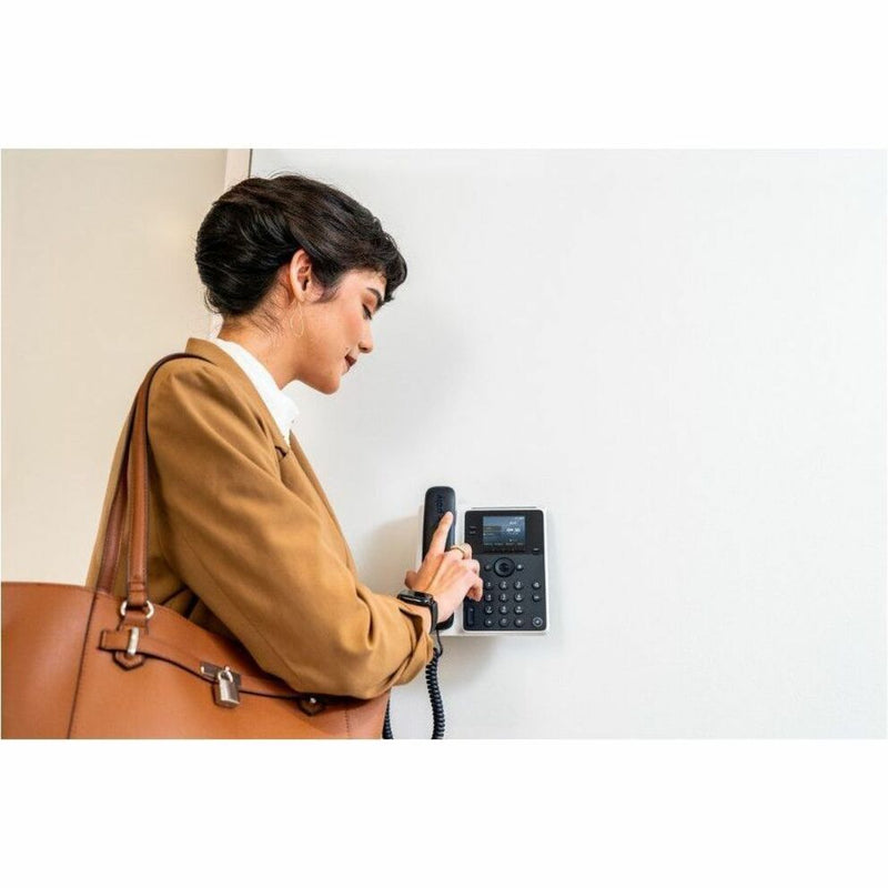 Professional using Poly Edge E100 IP phone in office setting