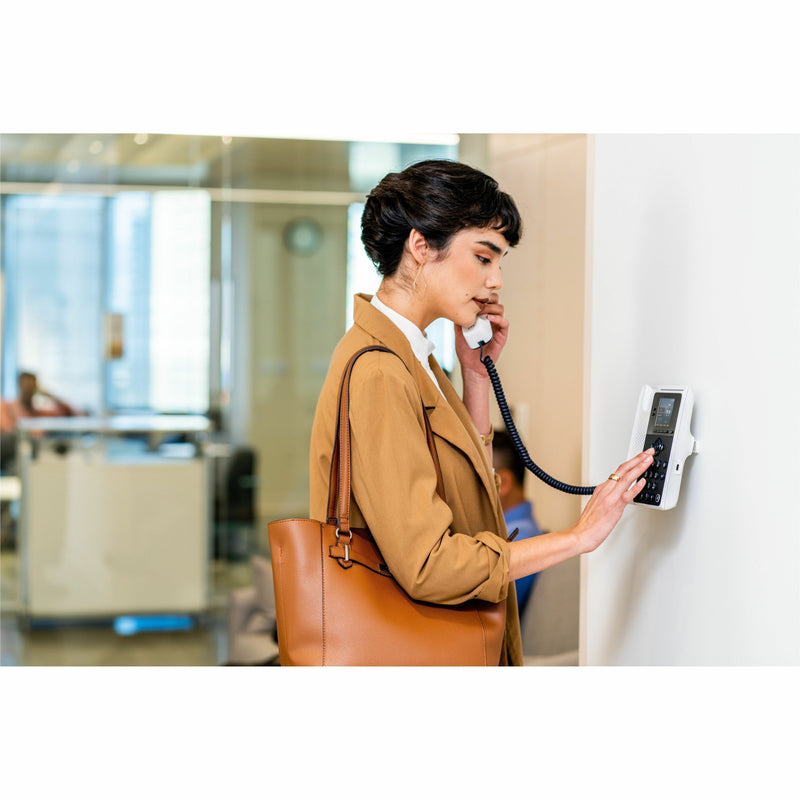 Professional using Poly Edge E100 IP phone in office setting