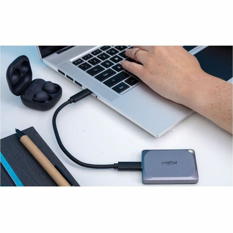 Crucial X9 Pro SSD connected to laptop with accessories on desk