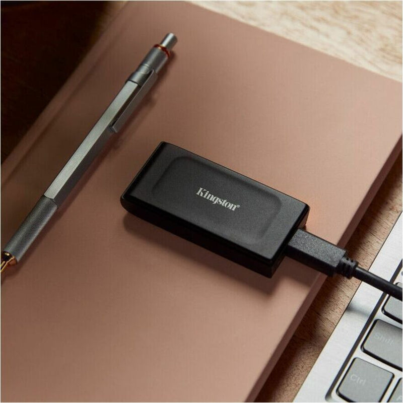 Close-up of Kingston XS1000 External SSD on desk with notebook