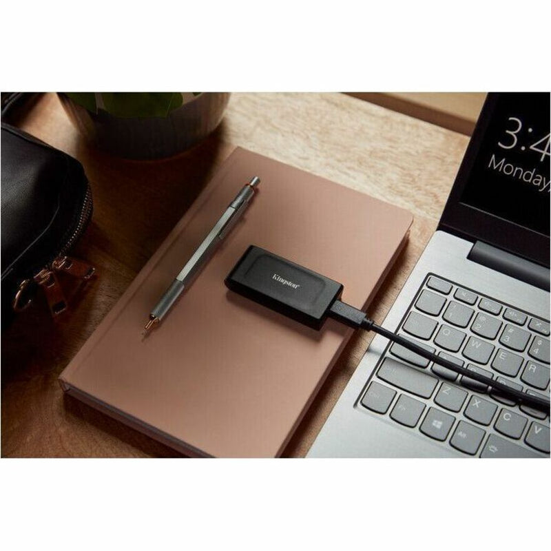 Kingston XS1000 External SSD connected to laptop on desk with accessories