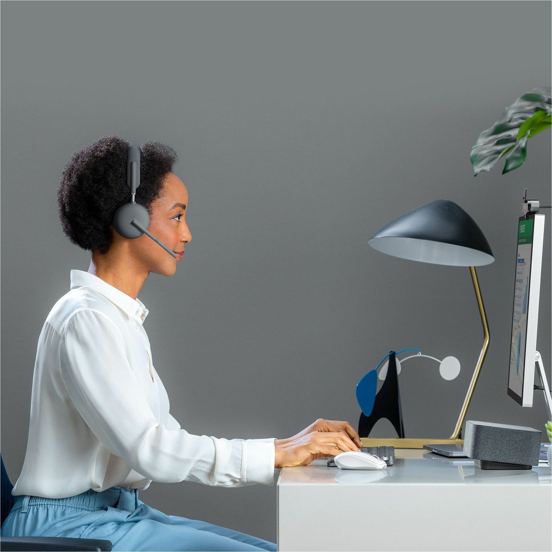 Side profile of professional wearing Logitech Zone Wireless 2 headset while working at desk setup-alternate-image4