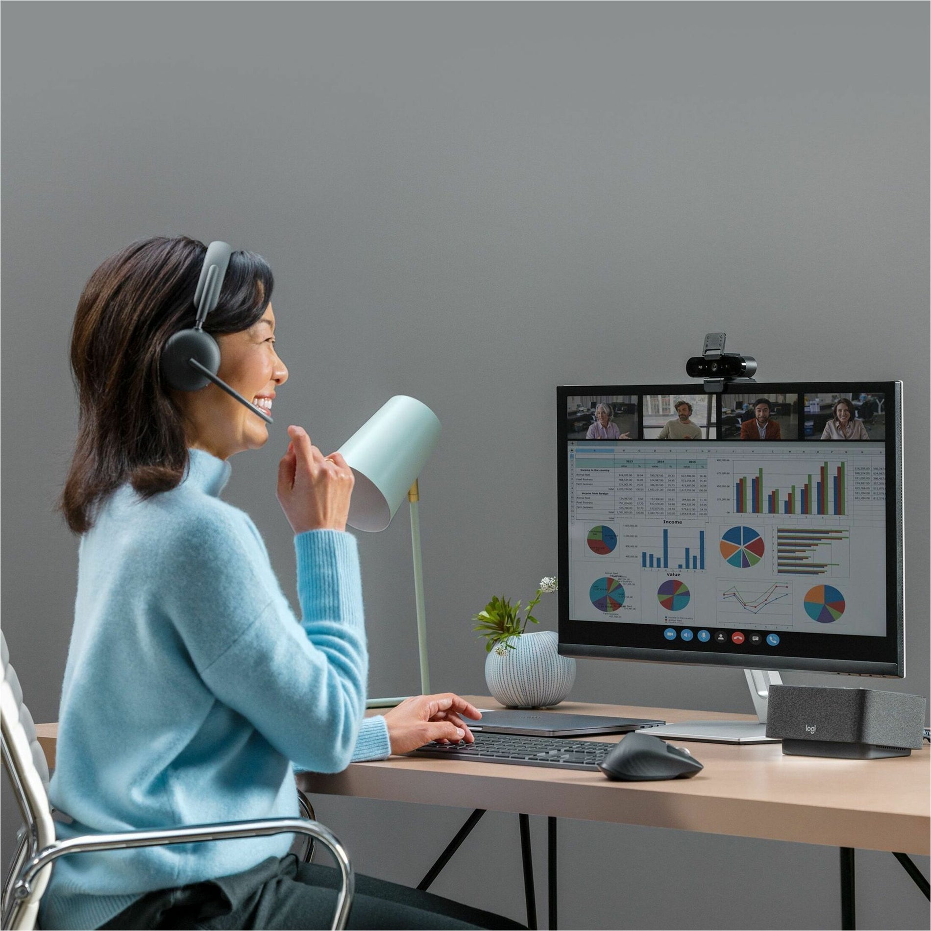 Professional using Logitech Zone Wireless 2 headset during a virtual meeting with multiple participants and data visualization on screen-alternate-image3