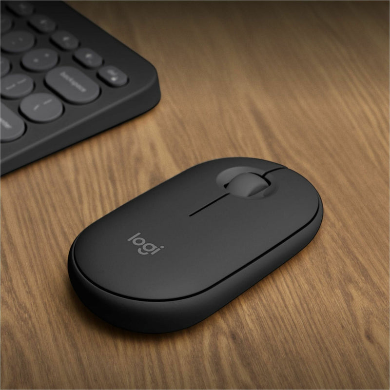 Logitech Pebble 2 M350s mouse on wooden desk surface with keyboard in background