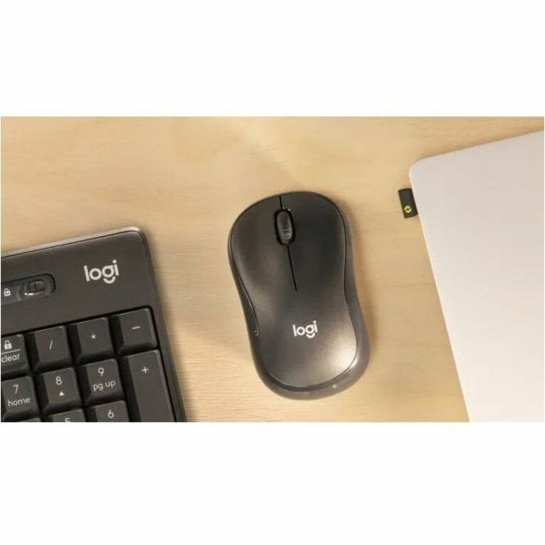 Close-up view of Logitech M240 mouse next to keyboard on wooden desk