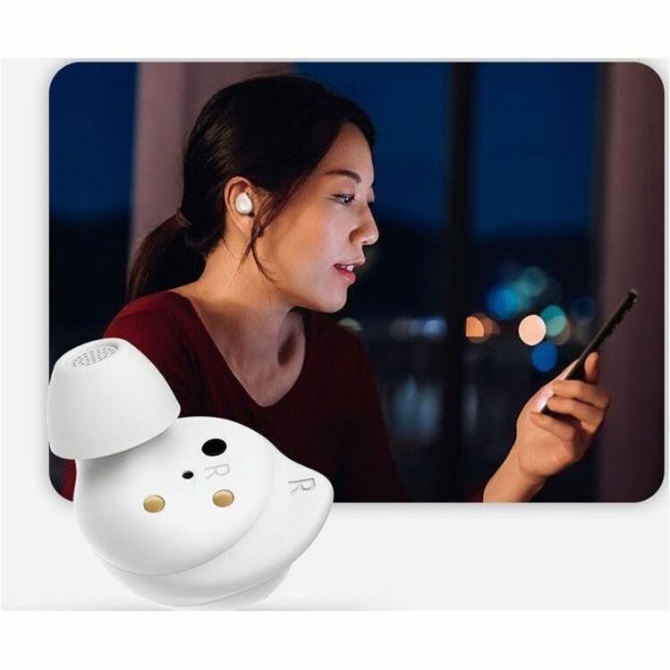 Person using Galaxy Buds FE while looking at smartphone in evening setting