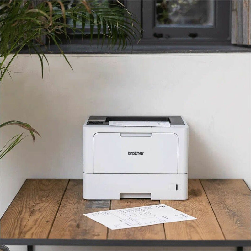 Brother printer in office setting with plants and wooden desk